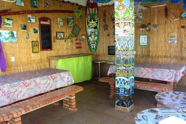 Tiki bar dining area with bamboo walls and surfboards